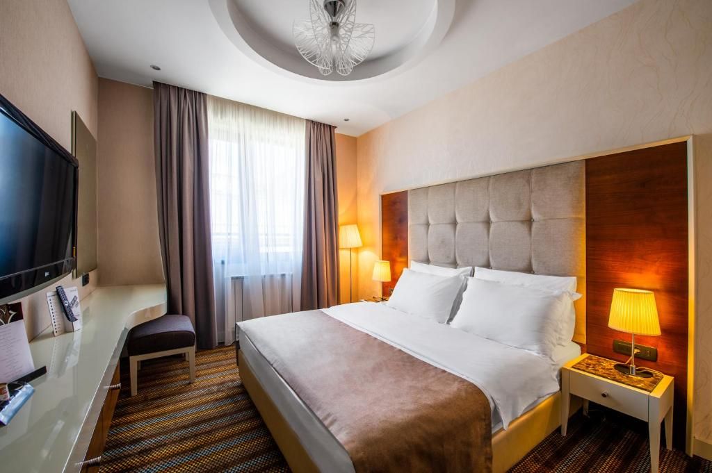 Una habitación de hotel con una cama grande, televisión, escritorio y una silla.