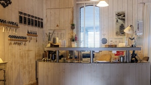 Un área de recepción con un mostrador de madera, una ventana con persianas y varios carteles y adornos en las paredes.