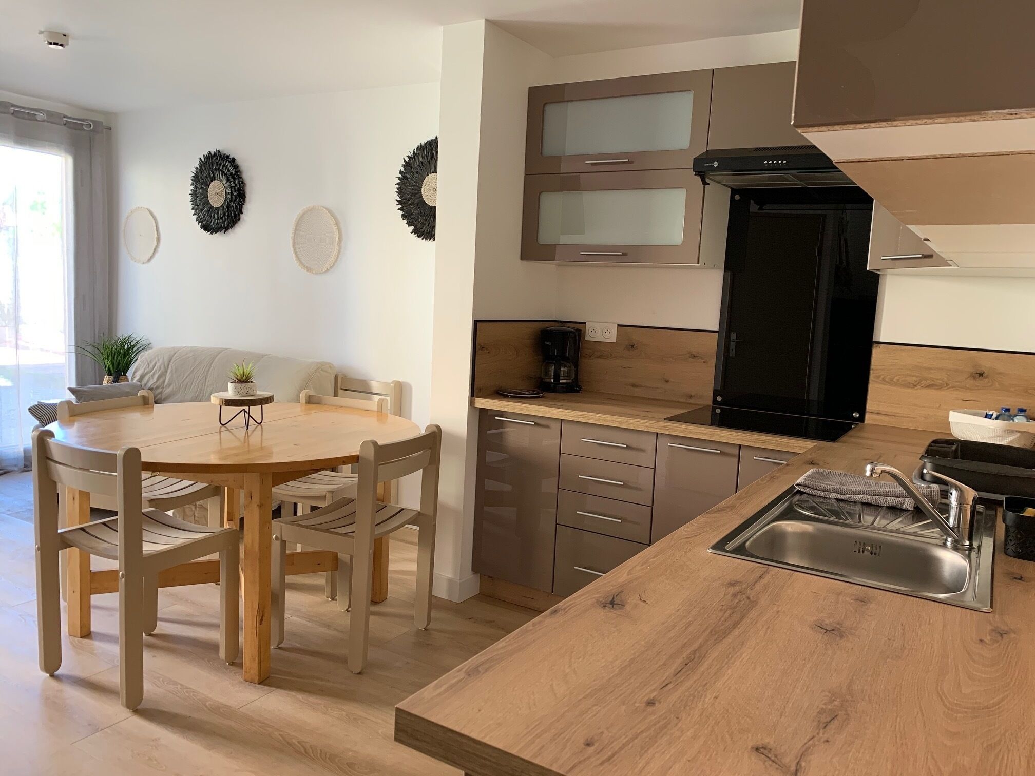 A modern kitchen with wooden cabinetry, a built-in oven, and a coffee maker.