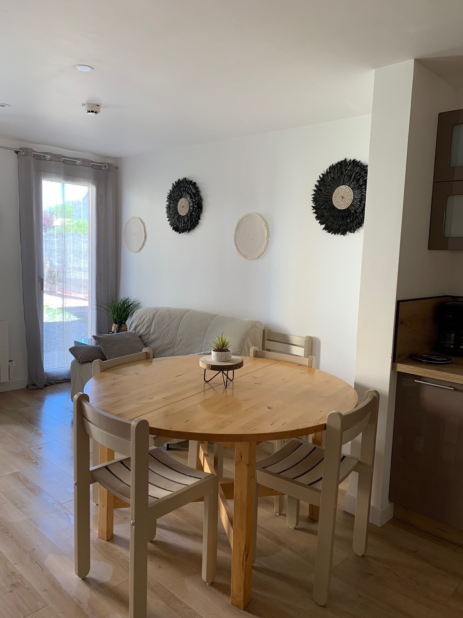Un coin repas comprenant une table ronde en bois, quatre chaises, un canapé et trois éléments décoratifs fixés au mur.