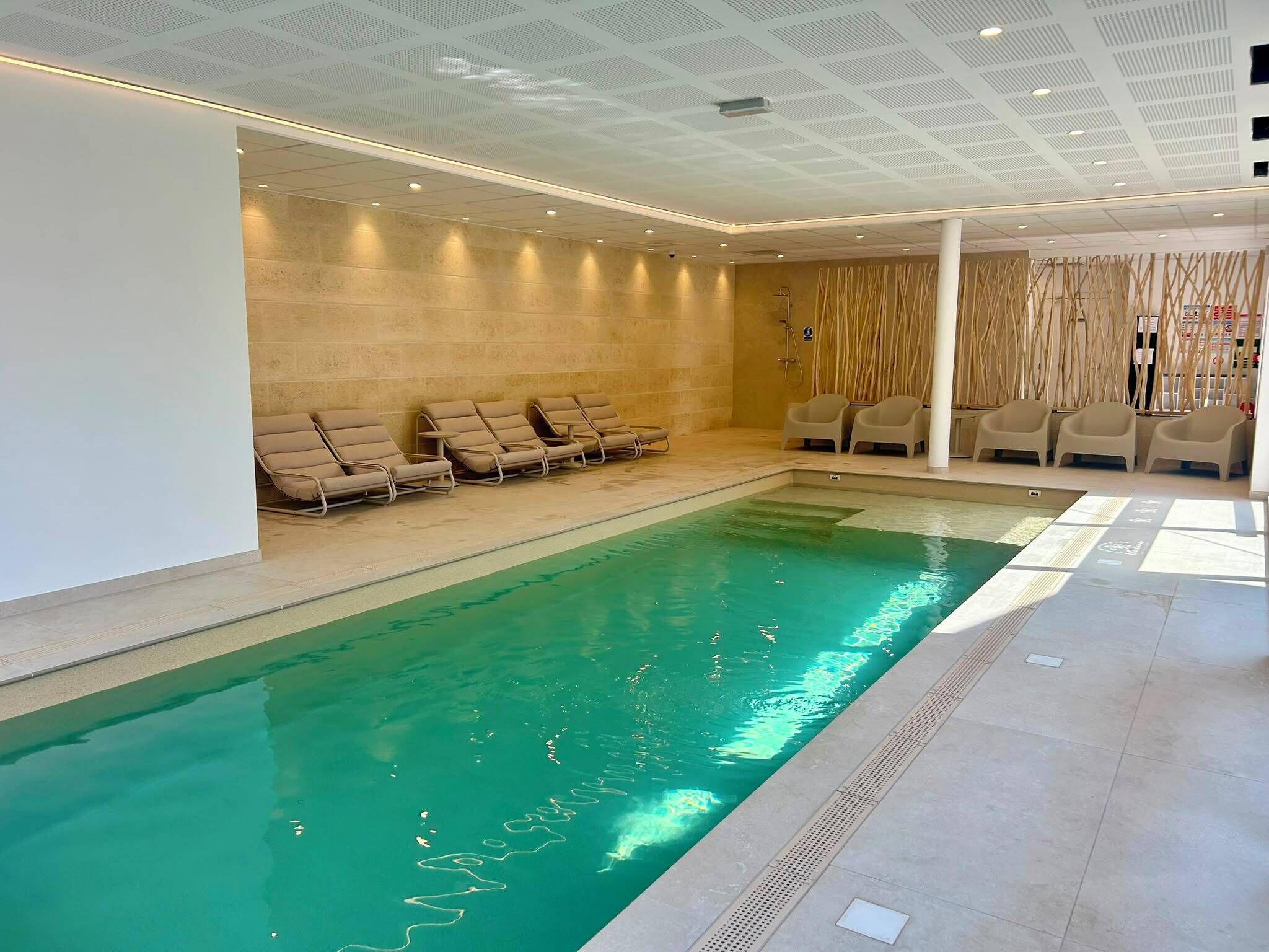 A swimming pool with lounge chairs and a spa area.
