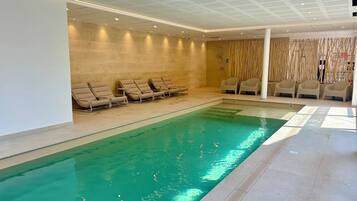 A swimming pool with lounge chairs and a spa area.