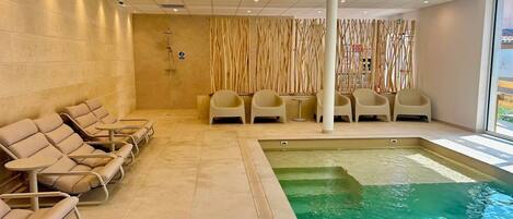 A spa area with a pool, lounge chairs, and a seating area with tables.