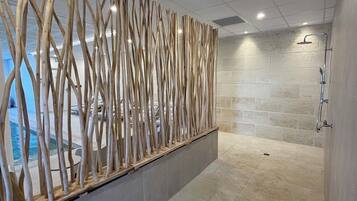 A modern bathroom with a glass shower enclosure, a decorative wooden panel, and a tiled floor.