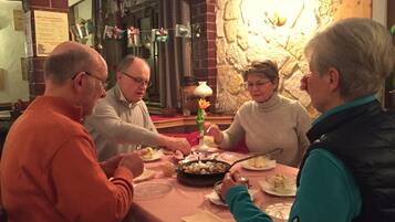 A group of people dining at a table with a brick wall and a stone fireplace in the background.
