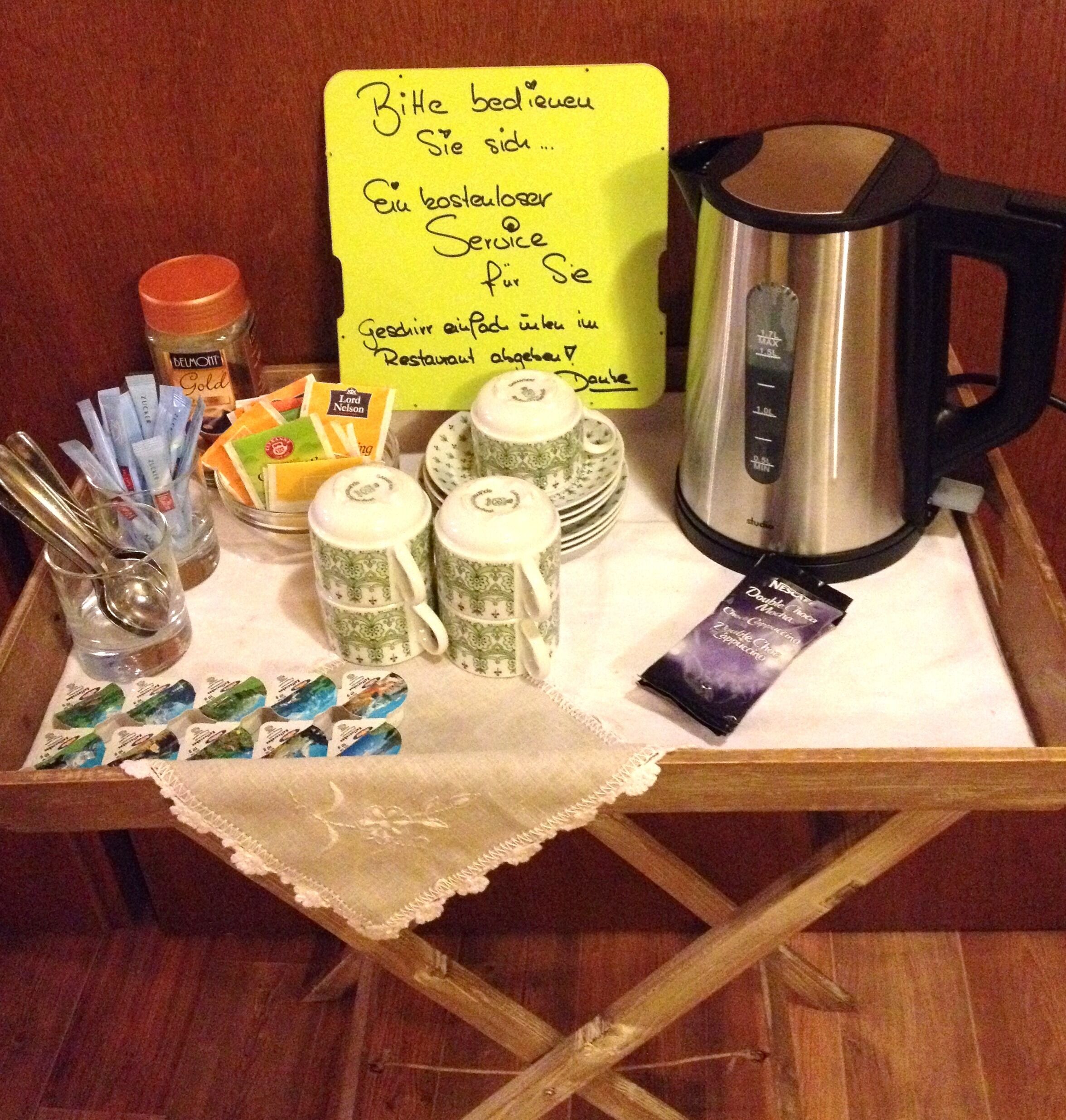 Un plateau avec une cafetière, des sachets de thé, un pot de sucre et un mot.