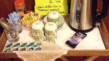 Un plateau avec une cafetière, des sachets de thé, un pot de sucre et un mot.