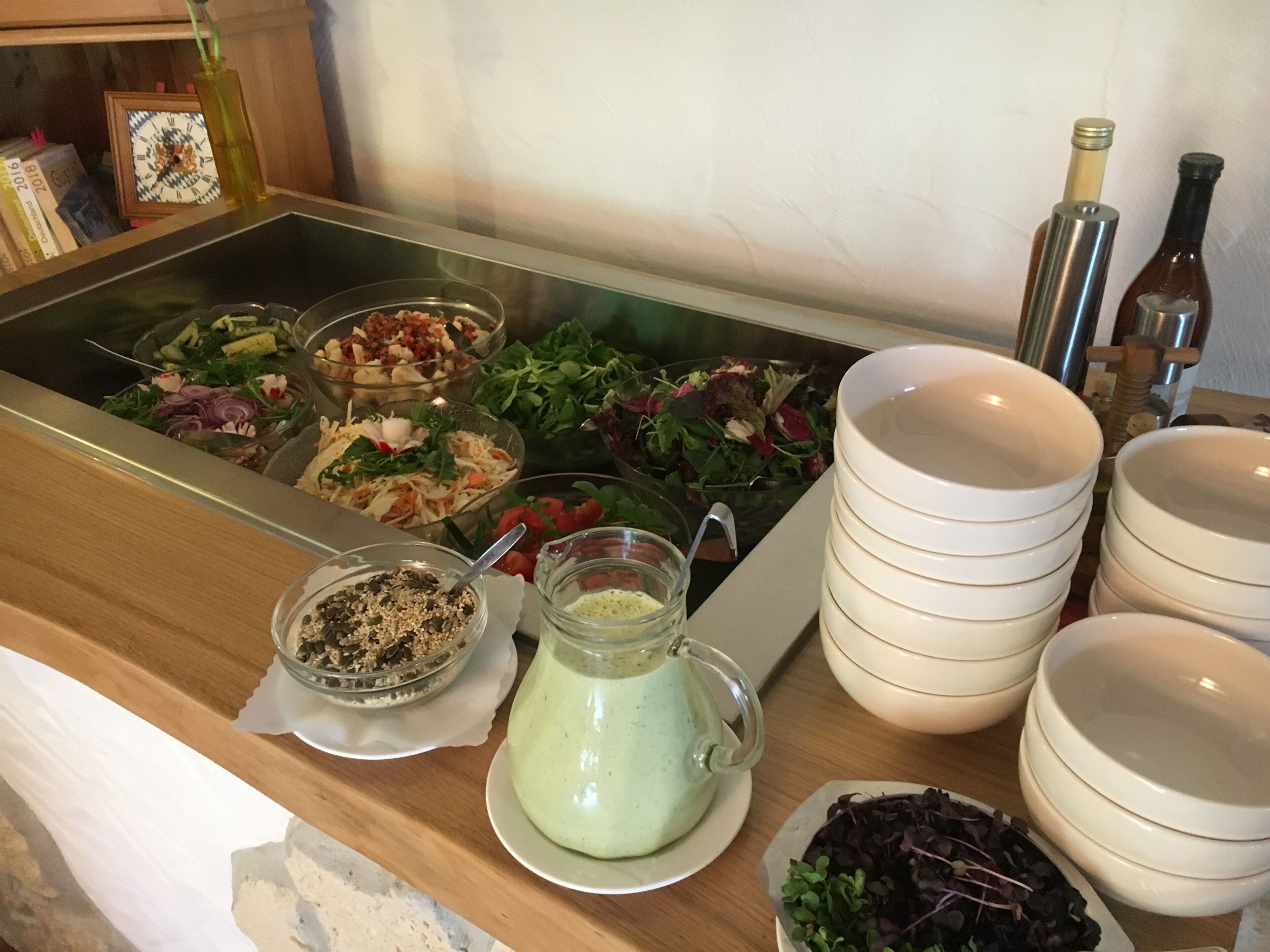 Ein Buffet mit verschiedenen Salaten und einer Kanne grüner Soße.