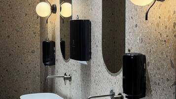A modern bathroom with two white sinks, a large mirror, and wall-mounted lighting fixtures.