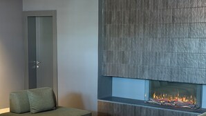 Una sala de estar moderna con chimenea, sofás verdes y una mesa de centro de mármol.