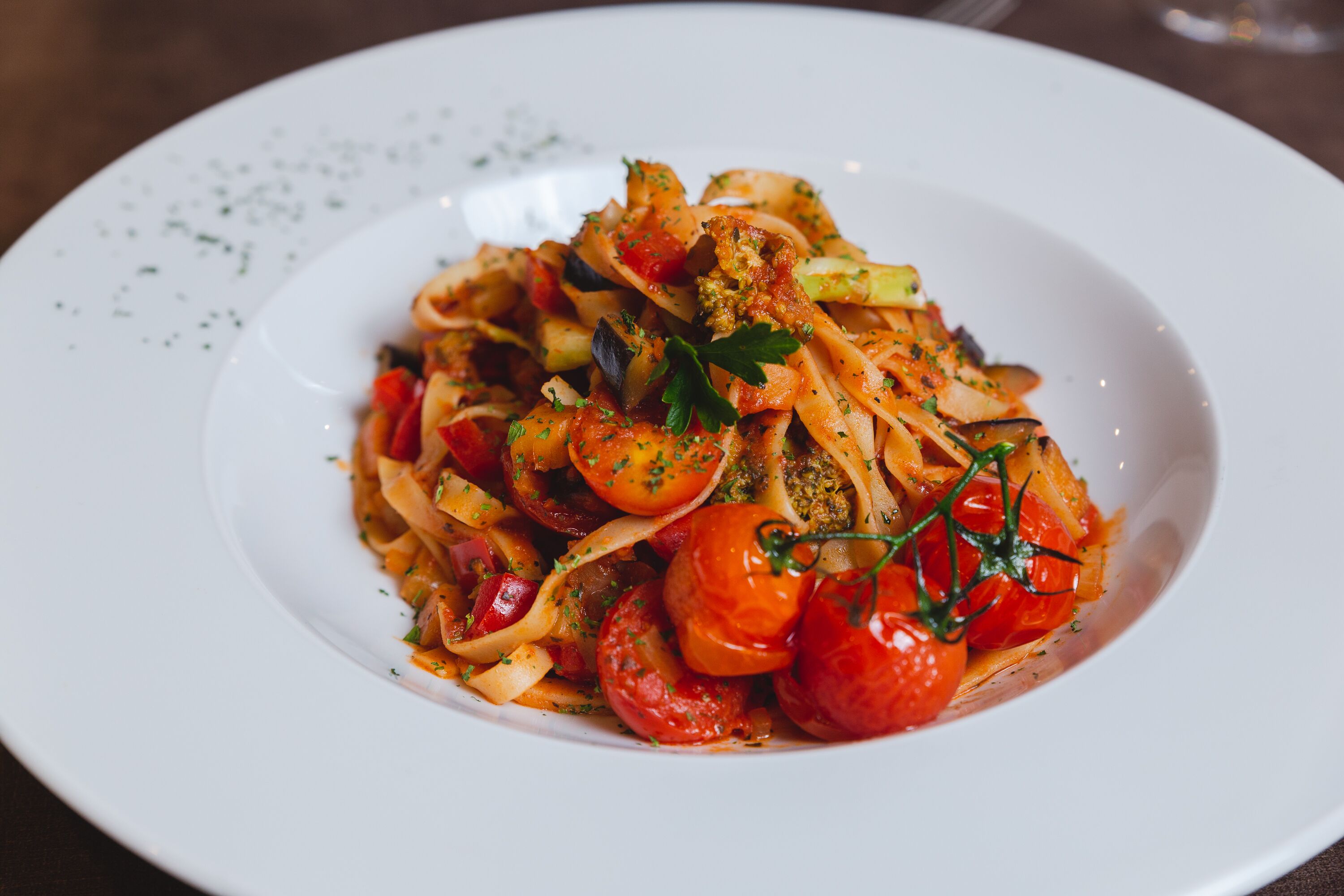 A plate of pasta with cherry tomatoes and herbs.