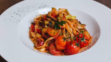 A plate of pasta with cherry tomatoes and herbs.