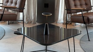 Una habitación moderna con dos sillones de cuero, una mesa de vidrio y un pilar grande.
