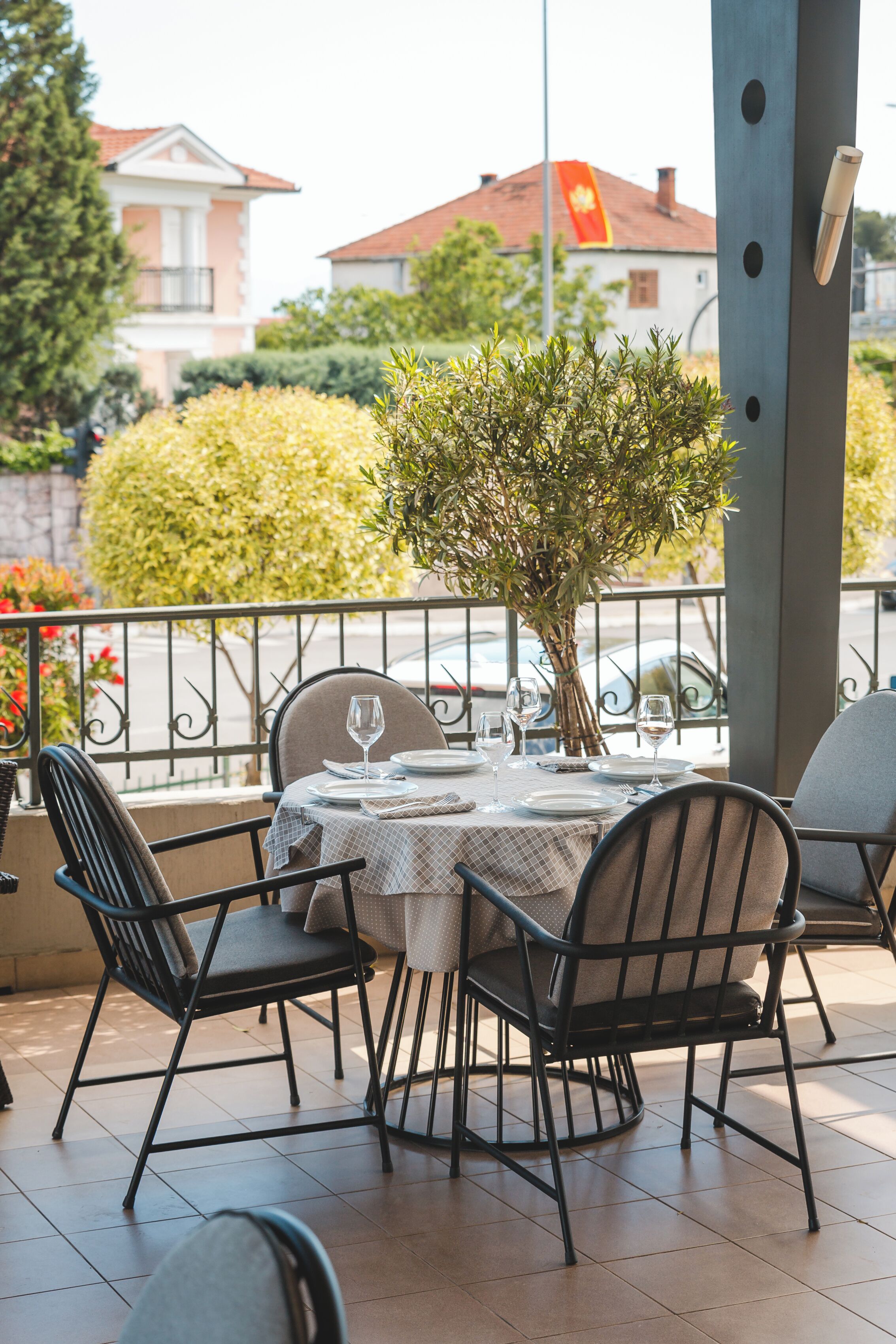 Un espace extérieur aménagé pour prendre les repas, avec une table dressée pour deux personnes, entourée de chaises, et une plante en pot.