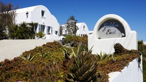 A white building with a sign reading "Golden East." - Golden East Hotel (Santorini)