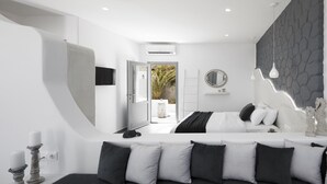A modern bedroom with a bed, bedside table, and a view of the outdoors. - Golden East Hotel (Santorini)
