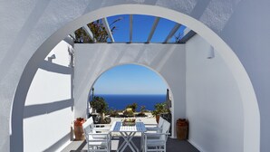 A white arched outdoor seating area with a view of the sea. - Golden East Hotel (Santorini)