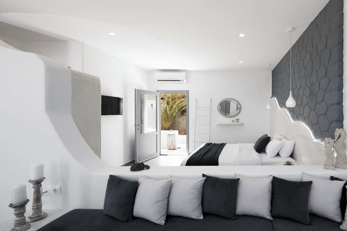 A modern bedroom with a bed, bedside table, and a view of the outdoors.