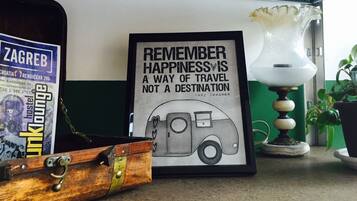 A framed quote about happiness and travel, a vintage suitcase, and a lamp on a table.