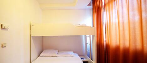 A bunk bed room with a window and curtains.