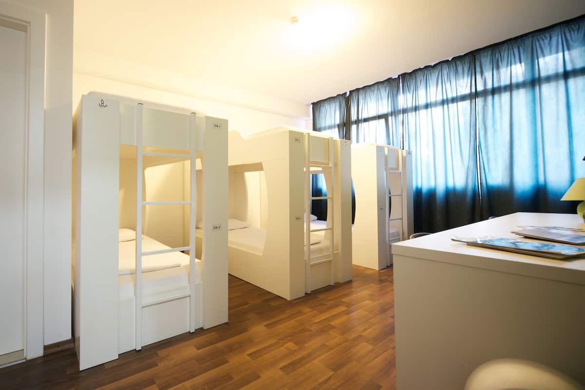 Ein Zimmer mit Etagenbetten, einem Schreibtisch und einem Fenster mit Vorhängen.