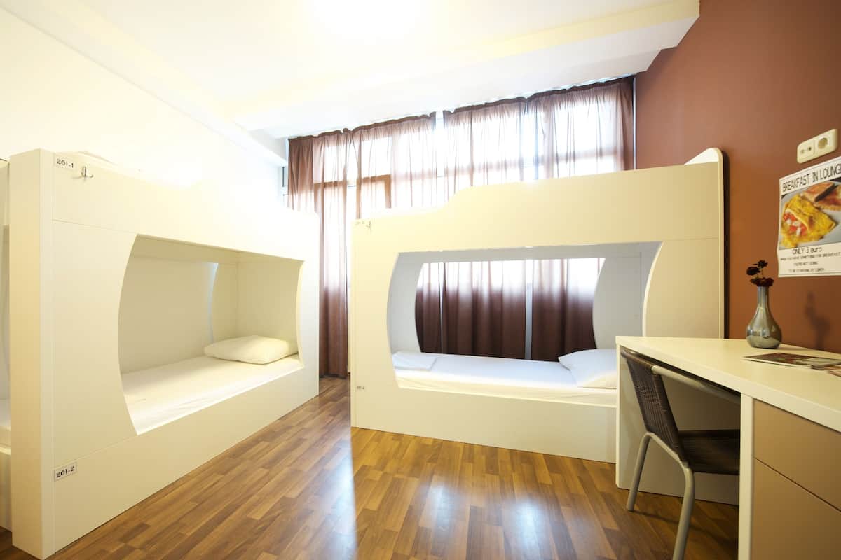Ein Zimmer mit Etagenbetten, einem Schreibtisch und einem Stuhl.
