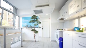 Una cocina moderna con armarios blancos, horno integrado y ventana con vistas a la ciudad.
