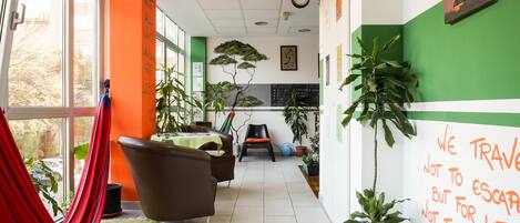 A hallway with a hammock, chairs, and potted plants.