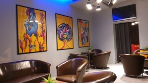 Un área de estar moderna con sillones de cuero, un televisor de pantalla plana en la pared y obras de arte coloridas en las paredes.