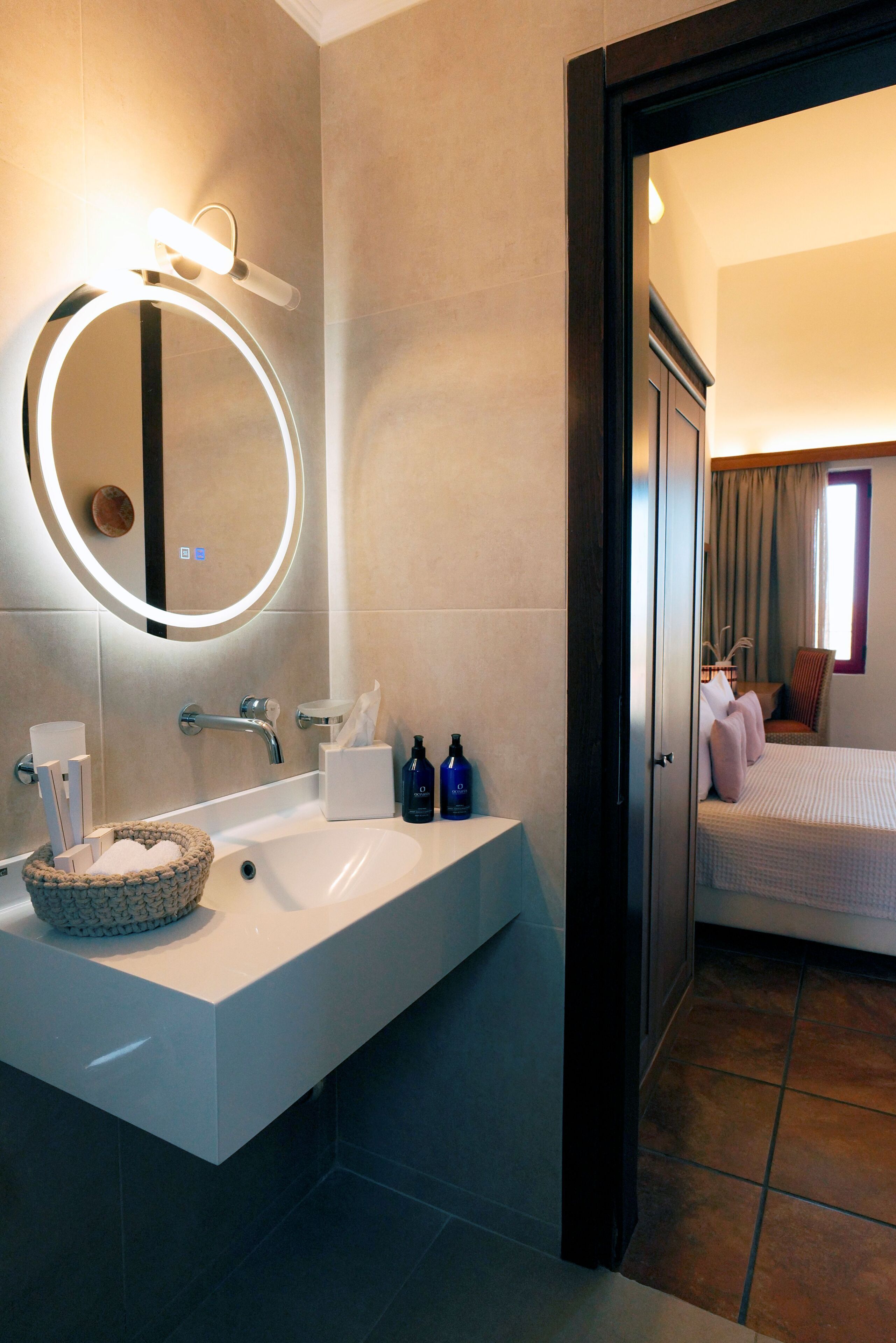 Une salle de bain moderne avec un grand lavabo, un miroir avec éclairage intégré et une petite baignoire ronde.