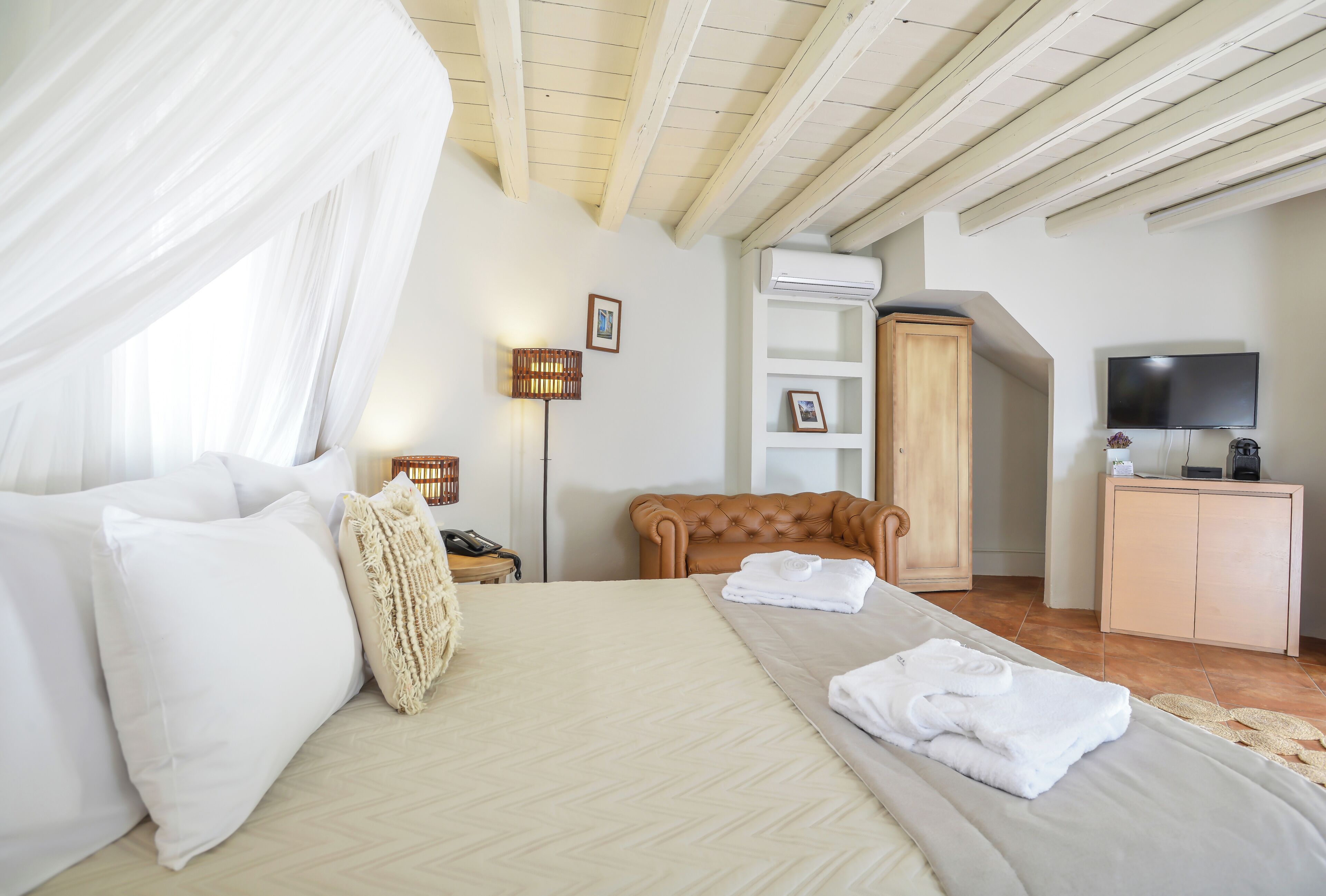 Quarto com cama, cabeceira de madeira, guarda-roupa, televisão e ar condicionado.