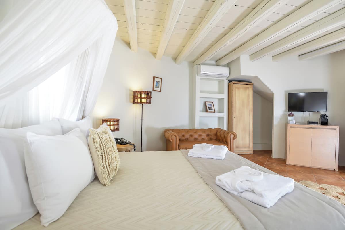 A bedroom with a bed, a wooden headboard, a wardrobe, a television, and an air conditioning unit.