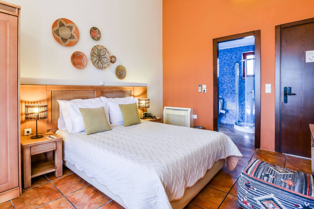 A neatly arranged bedroom with a bed, bedside lamps, a small table, and decorative wall art.