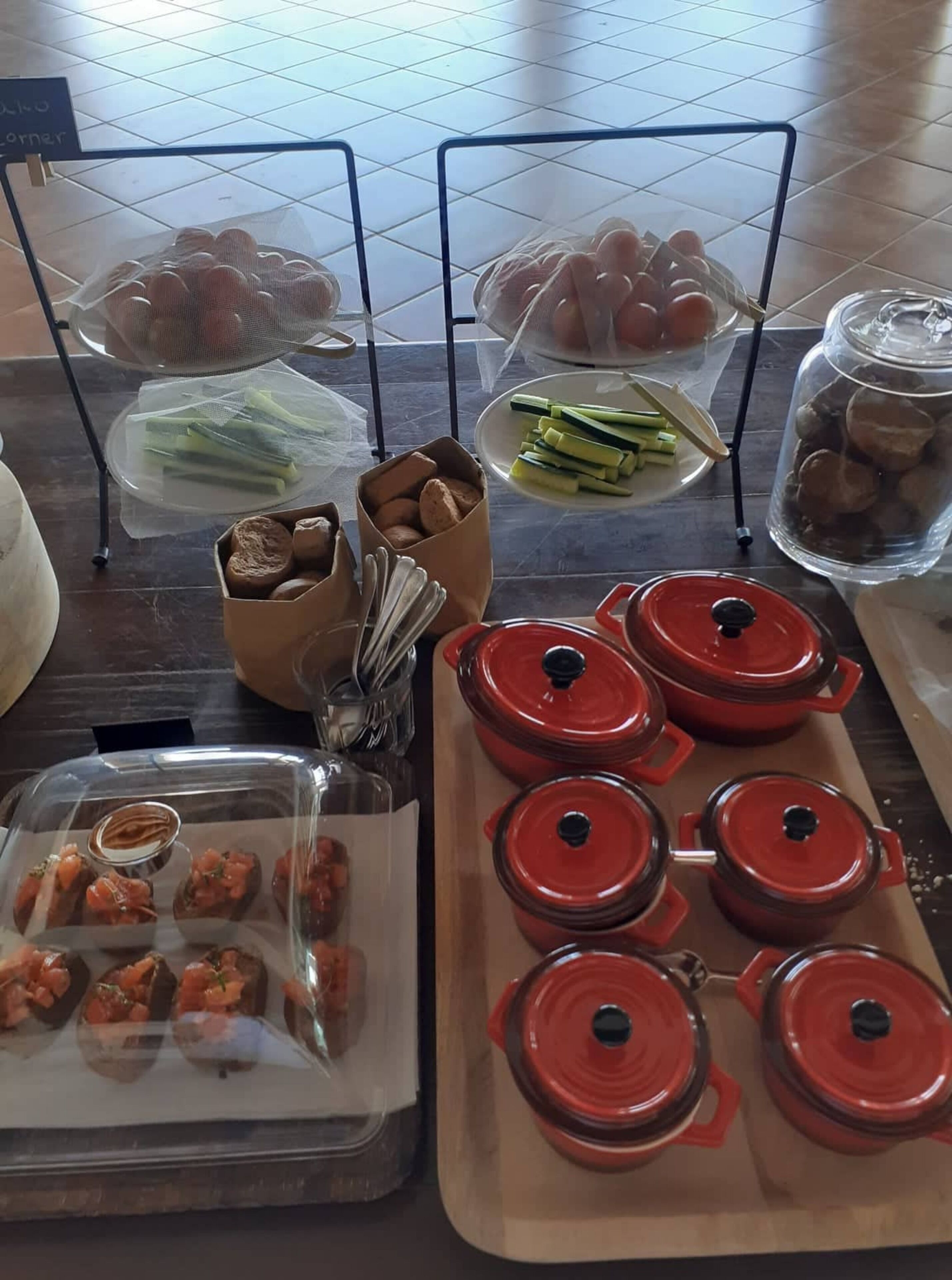 A buffet table with various food items, including bread, vegetables, and sauces in containers.