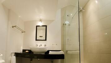 A modern bathroom with a large white sink, a glass shower enclosure, and a curved ceiling.