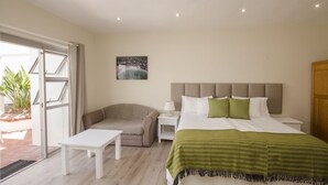 A bedroom with a bed, bedside table, nightstand, and a view of the outdoors. - Small Bay Guest House (Cape Town)