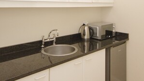 A compact kitchen with a sink, a kettle, a toaster, and a dishwasher. - Small Bay Guest House (Cape Town)