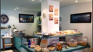 Un bufé de desayuno con diversas opciones de comida y bebidas, un reloj y decoración en la pared.