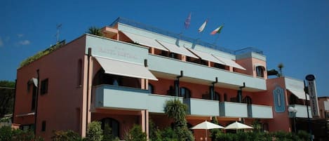 A hotel with a flat roof, multiple balconies, and a sign reading "HOTEL MISTRAL".