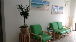 Una habitación con dos sillones verdes acolchados, una planta en maceta y dos cuadros en la pared.