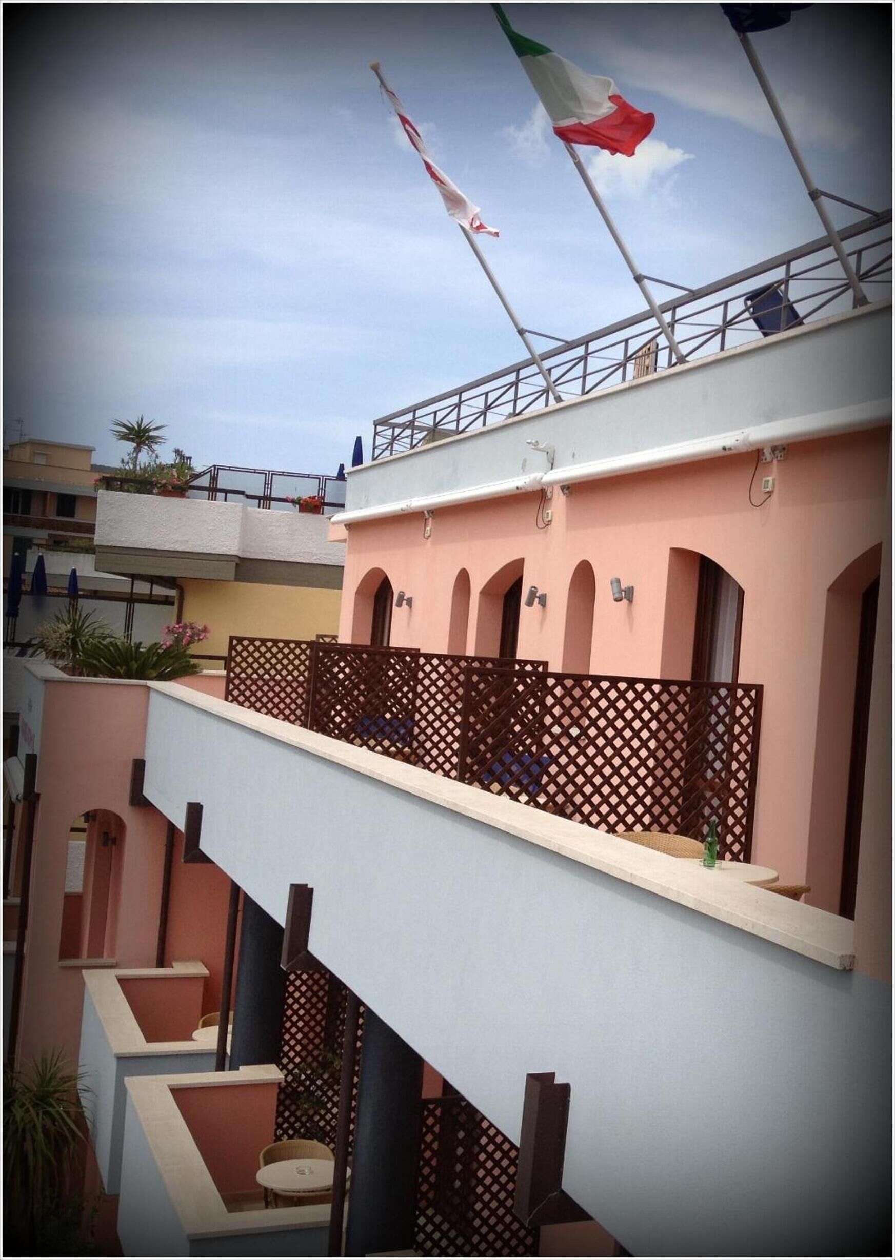 Un edificio de varios pisos con balcones, ventanas arqueadas y una bandera en el tejado.