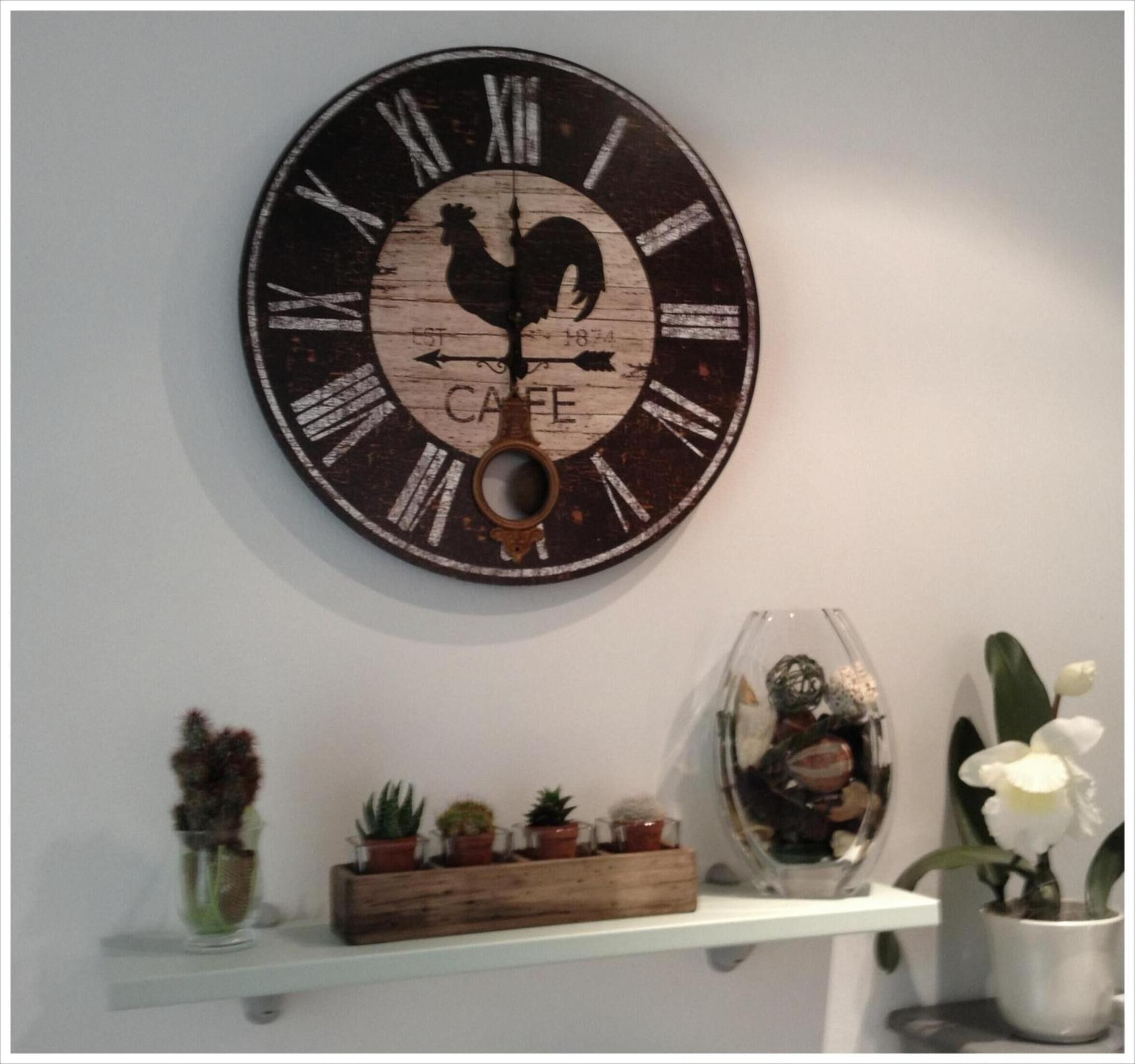 Une horloge murale ornée d’une silhouette de coq et du mot « CAFÉ » inscrit sous les chiffres romains.