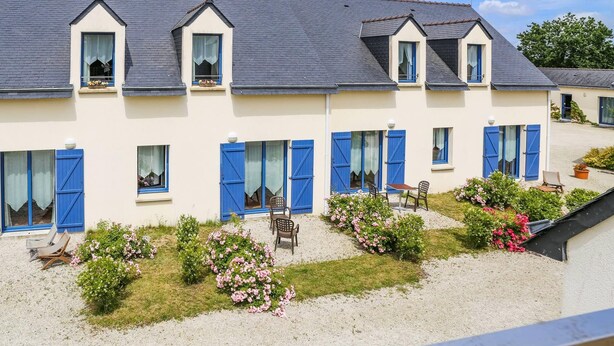 A two-story building with blue shutters and a gravel courtyard with flowers and chairs. - Hôtel le Chevalier Gambette (Saint-Armel)