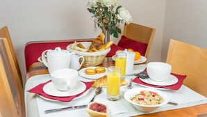 A breakfast setting with croissants, orange juice, and a vase of flowers on a table. - Hôtel le Chevalier Gambette (Saint-Armel)