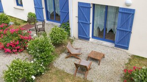 A building with blue shutters, a gravel patio, and outdoor seating. - Hôtel le Chevalier Gambette (Saint-Armel)
