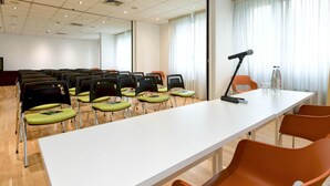 Een vergaderruimte met een lange tafel, stoelen, een beamer en een waterfles op de tafel.