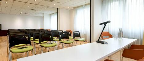A conference room with a long table, chairs, a projector, and a water bottle on the table.
