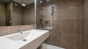 Een moderne badkamer met een grote wastafel, een spiegel en een douche.