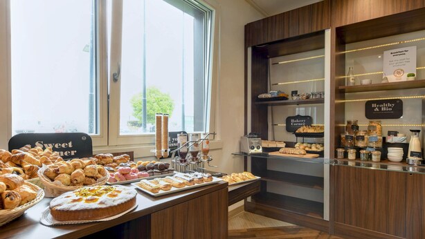 Een bakkerij toonbank met diverse gebakken producten en een bord met de tekst 'Sweet Corner'.