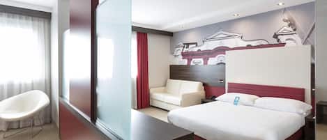Una habitación de hotel con una cama, un sofá, una silla y un ventanal grande.